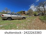 Small photo of Old, decrepit, dented, scratched car left aside among rusty facilities for agricultural and livestock use, farmland at the Galicica mountain foot in Elsani village. Ohrid municipality-North Macedonia.
