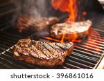 steaks cooking over flaming grill
