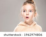 The child is a beautiful girl with wide eyes, look away in surprise. Baby in a knitted sweatshirt . Children's products , clothing and accessories . Expressive facial emotions