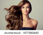 Brunette  girl with long  and   shiny wavy hair .  Beautiful  model with curly hairstyle .