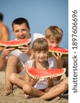 Small photo of happy father with children eating watermelon on the seabeach