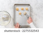 Flat lay. Scooping cookie batter with dough scoop into a baking sheet lined with parchment paper to bake banana cookies with chocolate drizzle.