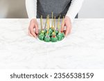 Small photo of Cactus-shaped cake pops, beautifully decorated with luster dust, sugar flowers, and white sprinkles, arranged in celebration of Cinco de Mayo.
