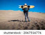 Adventurous female in the Great Sand Dunes National Park with a Sand Board