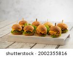 Set of Beef and Chicken mini burgers with cheese and lettuce with sticks on a wooden background 