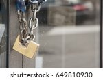 Brass padlock and chain on a glass door of a commercial premises in a safety and security concept