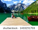 Woman relaxing on Pier at Lake Braies also known as Pragser Wildsee  in beautiful mountain scenery. Amazing Travel destination Lago di Braies in Dolomites, South Tyrol, Italy, Europe.