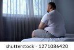 Small photo of Sad heavy man sitting on bed at home, health problem, depression, insecurities