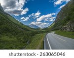 Curvy and lonely road between norwegian mountains under blue sky