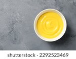 Homemade vanilla custard pudding or lemon curd in a white bowl. top view