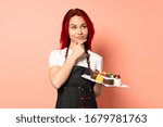 Pastry chef holding a muffins isolated on pink background thinking an idea while looking up