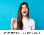 Small photo of Teenager girl over isolated blue background intending to realizes the solution while lifting a finger up