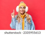 Small photo of Young pretty Uruguayan woman wearing winter muffs isolated on red background background intending to realizes the solution while lifting a finger up