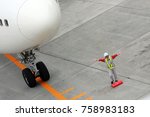 Small photo of SAPPORO, JAPAN - JUNE 15, 2009: Airfield worker showing the pilot of Japan Airlines (JAL) flight the cutoff point for a complete stop at New Chitose (Shin Chitose) Airport