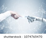 Human and robot hands reaching out and touching with index fingers. A gray background with a network hologram. Concept of hi tech