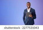Small photo of Cheerful young African American businessman holding tablet computer over purple background. Concept of social media. Mock up