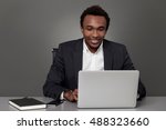 Small photo of Cheerful African American businessman is surfing the Internet at his workplace. Concept of being counterproductive