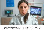 Small photo of Raw shaky portret of tired doctor in coverall taking off the mask looking on camera after examining patient during coronavirus pandemic. Dentist nurse wearing coverall, face shield, mask, gloves in