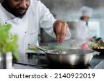 Small photo of Master chef wearing cooking uniform garnishing gourmet dish with fresh chopped herbs in restaurant kitchen. Gastronomy expert using pan to cook delicious food for dinner service.