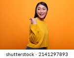 Small photo of Beautiful attractive woman showing cash gesture on payday while smiling heartily on orange background. Happy positive adult person enjoying salary payout while wearing yellow vibrant sweater.