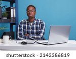 Small photo of Funny and goofy office working person making amusing playful face while sticking out tongue. Childish and dumb young adult man with dullard face expression while in company workspace.