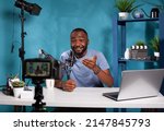 Small photo of Vlogger talking with audience in excitement in front of recording digital video camera during online live show. Exalted content creator in studio looking at dslr live video podcast setup gesturing.