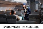 Small photo of Female stewardess asking passengers about airline services and flying, boarding travellers on airplane seats. Travelling with international airways, chatting on aeroplane jet and going on vacation.