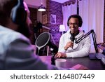 Multiethnic team of people meeting to record podcast episode together, creating online content with live broadcast discussion. Male vlogger talking to adult, livestream production.