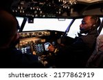 Small photo of African american pilot flying aircraft jet doing teamwork with captain, using dashboard command and navigation. Team of airliners pushing control panel buttons and lever to takeoff and fly.