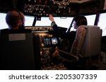 Small photo of Female pilot assisting captain to takeoff and fly airplane, using buttons on dashboard command in pilot cockpit. Airliners flying plane jet with navigation windscreen and control panel.