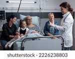 Small photo of Elderly bedridden man relatives happily attending care, prevention instructions of young doctor at hospital rest room. Laboratorist handing over elderly man clinical analysis to relatives in hospital.