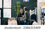 Small photo of African american robber trying to sneak stolen shirt being caught by store security guard in modern boutique. Bodyguard asking thief to return stylish merchandise or will call the police