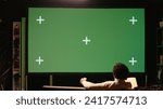Small photo of African american man using remote to zap through films available on streaming services on chroma key TV. Cord cutter having movie night in home theatre using green screen television set