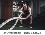 Muscular powerful aggressive man training with rope in functional training fitness gym