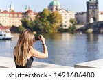Young female traveler taking a picture of the Bridge of Charles in Prague. Holidays concept.