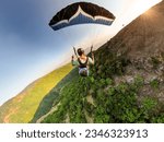 Small photo of Extreme paraglider pilot flying over Bulgarian mountains, adventure concept.