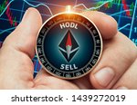 hand holding compass with glowing ethereum symbol and in front of stock market chart data. Compass needle showing HODL word. 