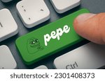 Close up photo of male hand finger pressing pepe memecoin computer key on keyboard. Cryptocurrrency mining or trading concept.