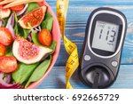 Fruit and vegetable salad, glucometer with result of measurement sugar level and tape measure, concept of diabetes, diet, slimming, healthy lifestyles and nutrition