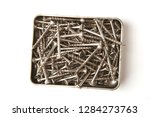 Stainless steel screws in box isolated on white background. Pile of wood screws top view.
