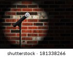 Artistic image of microphone against a rustic brick wall with spotlight effect and copy space.  Closeup with shallow dof.