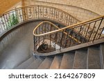 spiral staircase in the interior with marble floor and elegant wrought iron balusters with wooden railings