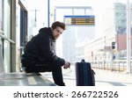 Portrait of a young man waiting for train with suitcase travel bag