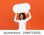 Happy young African American woman in plain white long sleeve t-shirt holding empty speech bubble isolated on orange  background