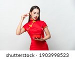 Beautiful Asian woman in traditional red Chinese qipao dress holding food box and chopsticks in studio isolated gray background