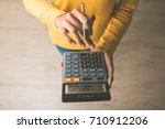 Woman entrepreneur using a calculator with a pen in her hand, calculating financial expense at home office