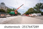 Unloading and installing concrete plates from truck by crane. Road construction site with tram tracks repair and maintenance timelapse hyperlapse on a middle part of intersection.