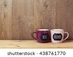 Coffee cups on wooden table with chalkboard sign and best friends text. Friendship day celebration background