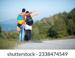 Young couple, backpackers, hitchhiking on a hilly road on a sunny day. Autostop adventure backpack concept. Back view