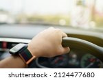 Unrecognizable male driver using left hand grabs on the steering wheel while driving on the road, man driving a car. Beautiful sunlight on the road during man drive a car. Safety driving concept.